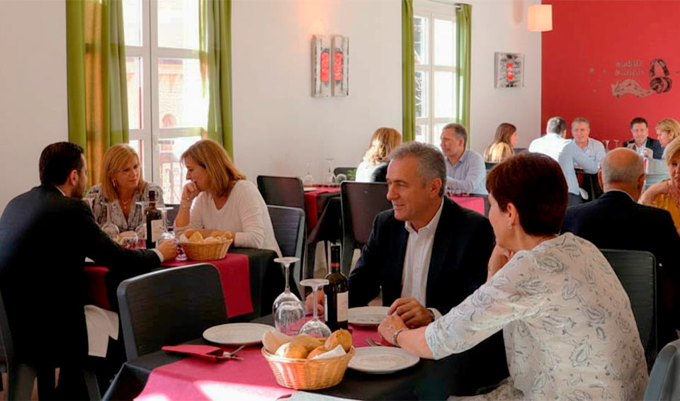 Comedor del Hotel Oleum con un grupo de personas disfrutando de una comida en un ambiente luminoso y acogedor.